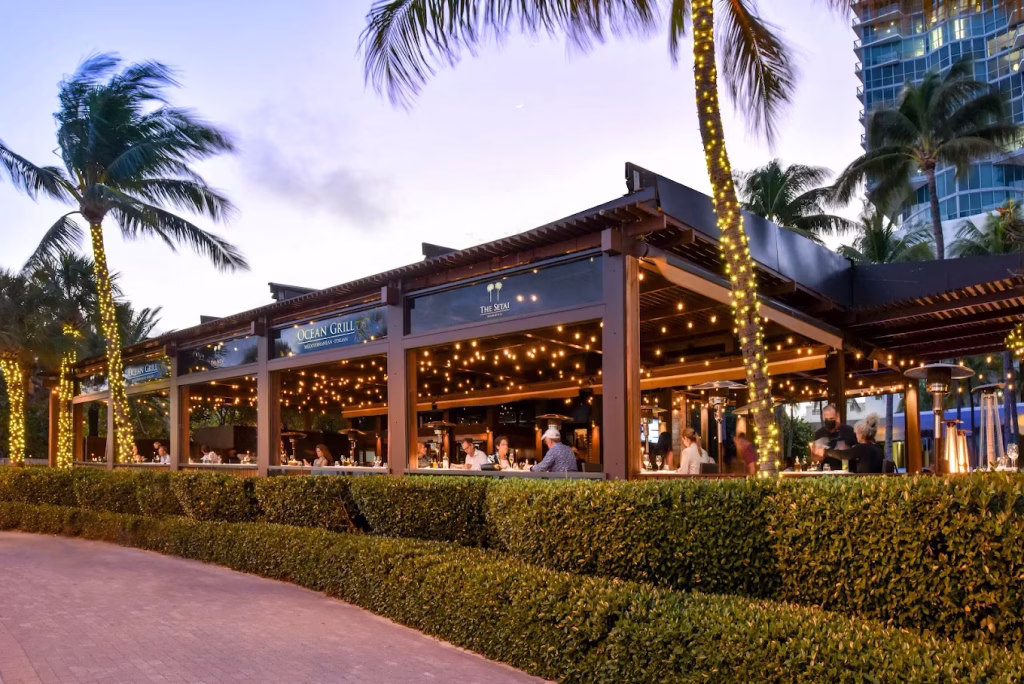 Open-air dining deck at Ocean Grill at The Setai with palm-framed beachfront seating in Miami Beach