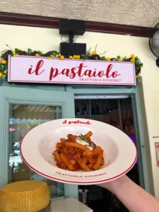 Plate of rigatoni held in front of the Il Pastaiolo entrance in Miami Beach