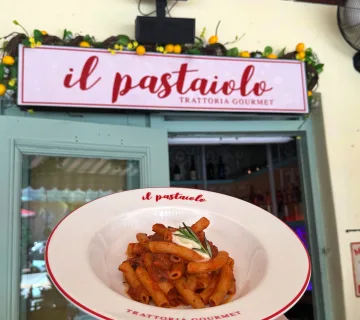 Plate of rigatoni held in front of the Il Pastaiolo entrance in Miami Beach
