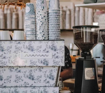 Blue patterned coffee cups and floral espresso machine on the Maman Miami Beach cafe counter.