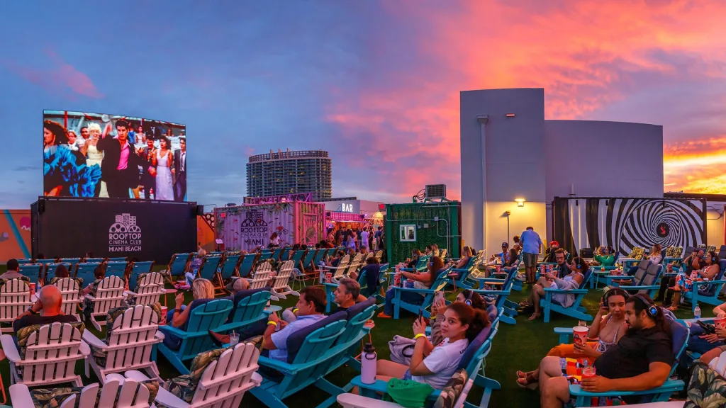 Rooftop Cinema Club Miami with outdoor screen, cozy lounge chairs, and city skyline views at sunset.