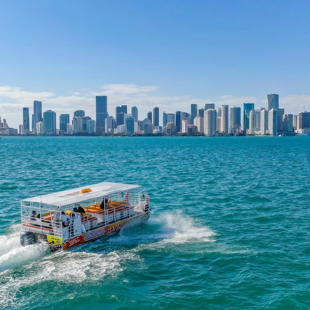 Miami Beach waterfront with water taxi cruising under clear blue skies.