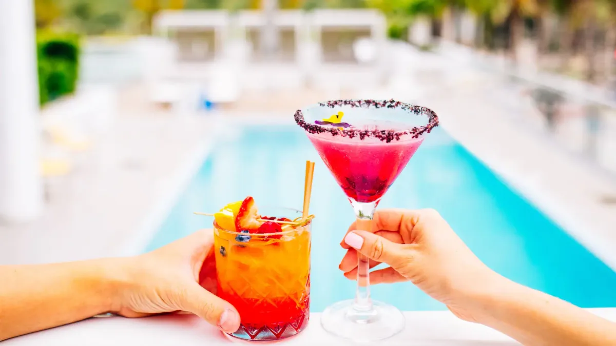 Happy Hour Cocktails by the Pool in Miami Beach Two colorful cocktails being toasted by a pool during happy hour in Miami Beach