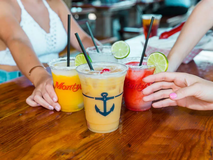 Friends holding tropical cocktails during happy hour at a lively Miami Beach bar