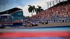 Formula cars speeding around the Miami Grand Prix circuit with fans watching