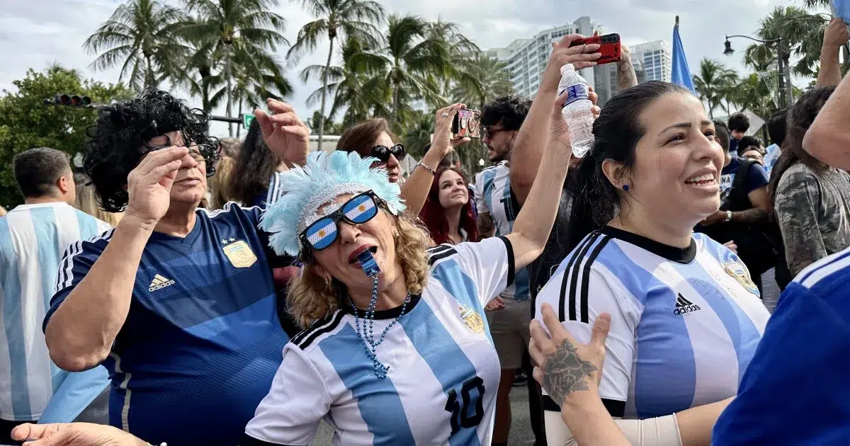 Soccer fans wearing Argentina jerseys celebrating at a FIFA Fan Festival during a World Cup viewing event in Miami.