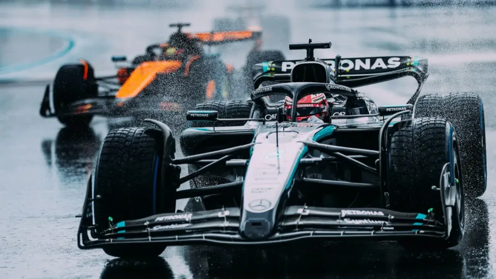 Formula 1 cars racing on a wet track in heavy rain with water spray and low visibility during a stormy race