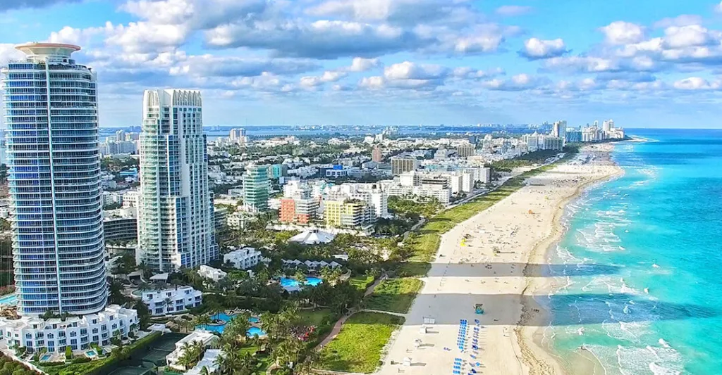 South Beach shoreline with white sand, blue water, and palm trees.