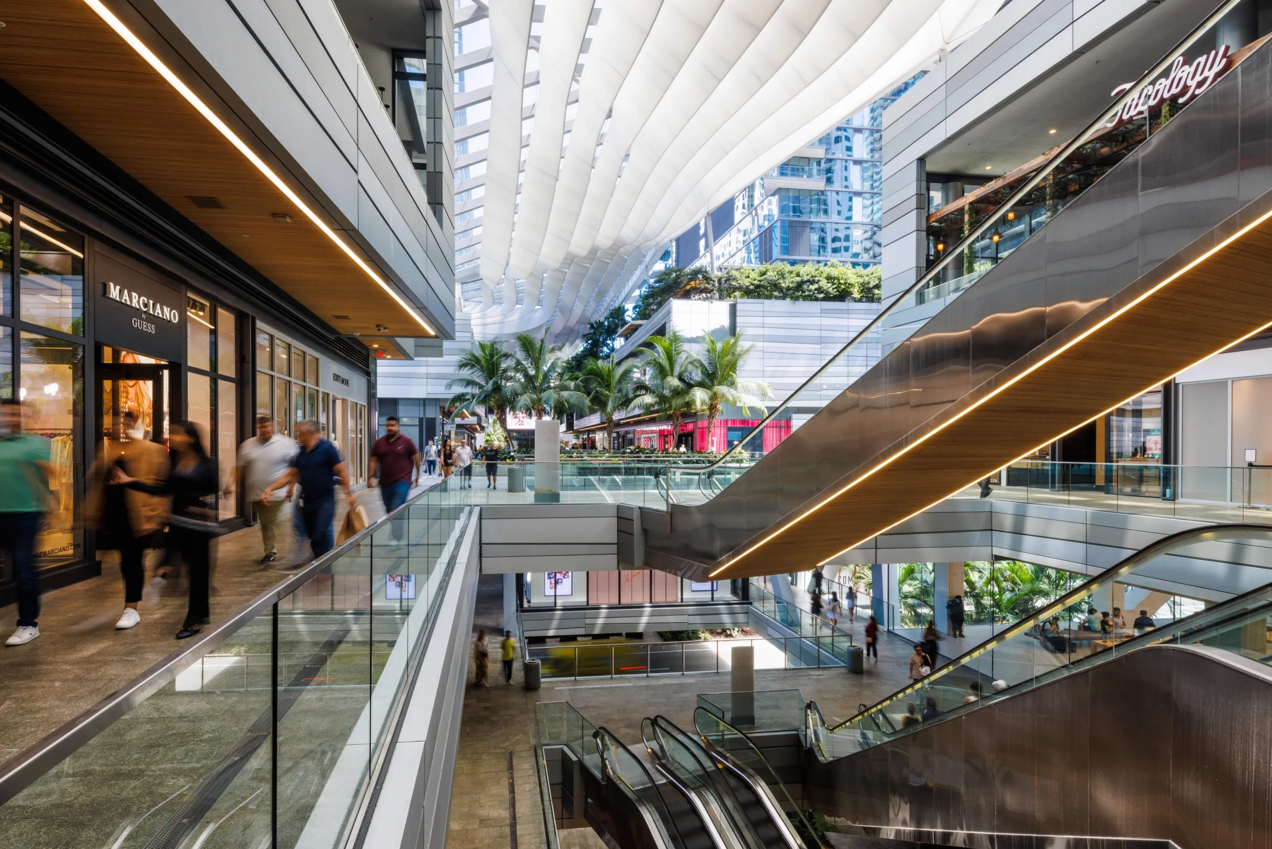 Interior view of Brickell City Centre in Miami with escalators, modern design, and shoppers exploring the mall