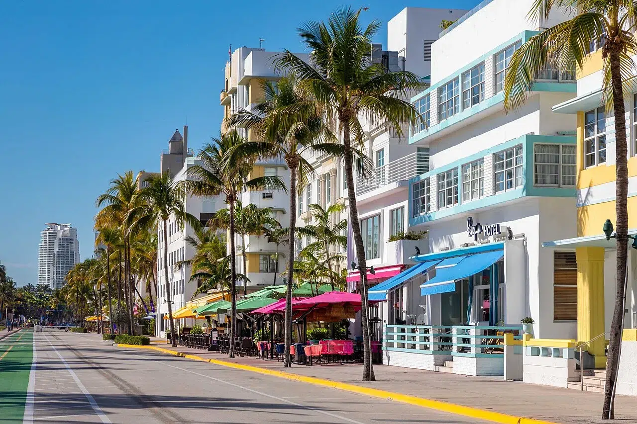 Palm tree-lined street in South Beach Miami featuring colorful Art Deco hotels, outdoor dining, and sunny coastal atmosphere near Ocean Drive.