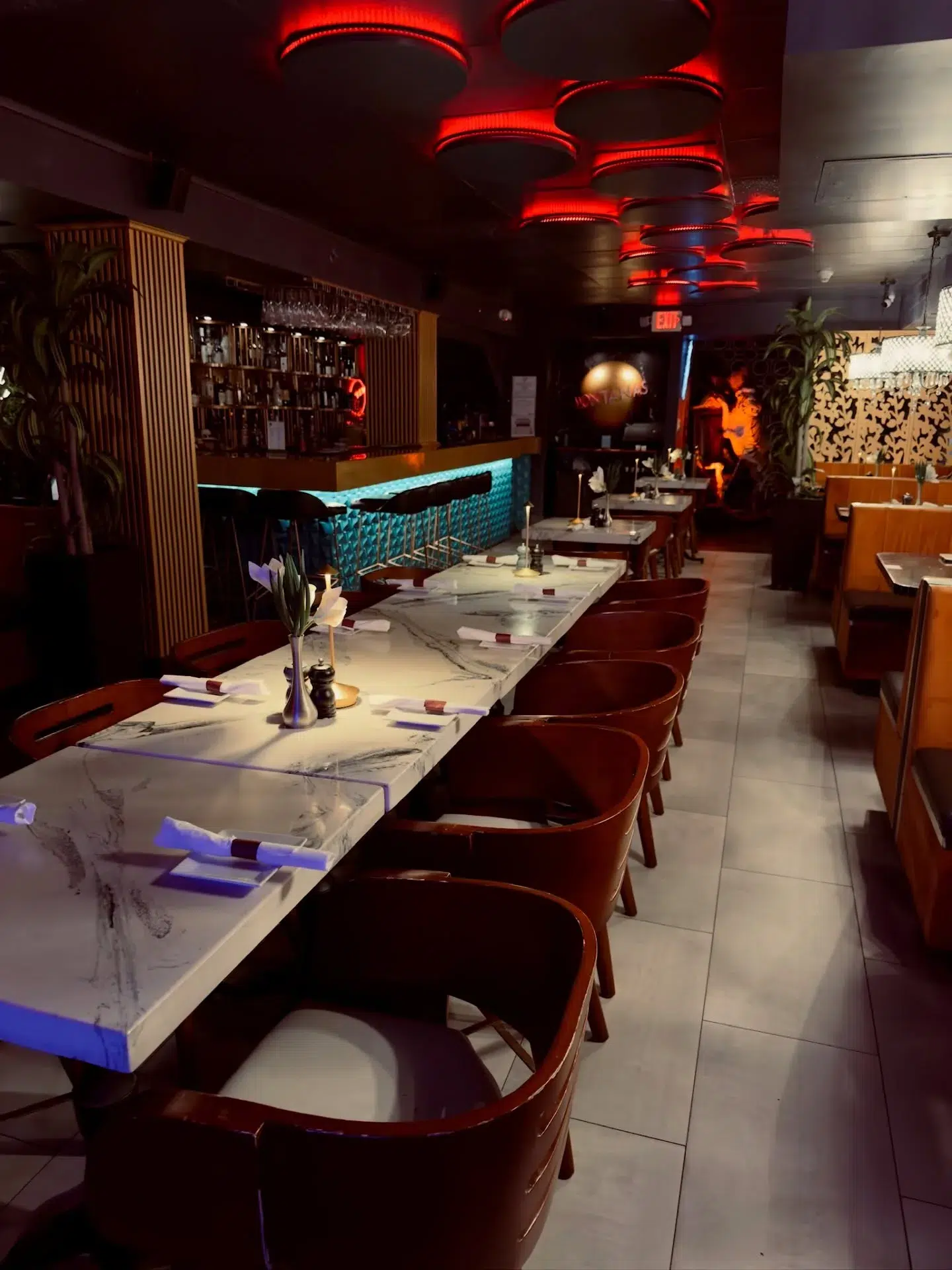 Modern upscale Miami restaurant interior with marble tables, ambient red lighting, stylish seating, and luxury nightlife-inspired dining atmosphere.