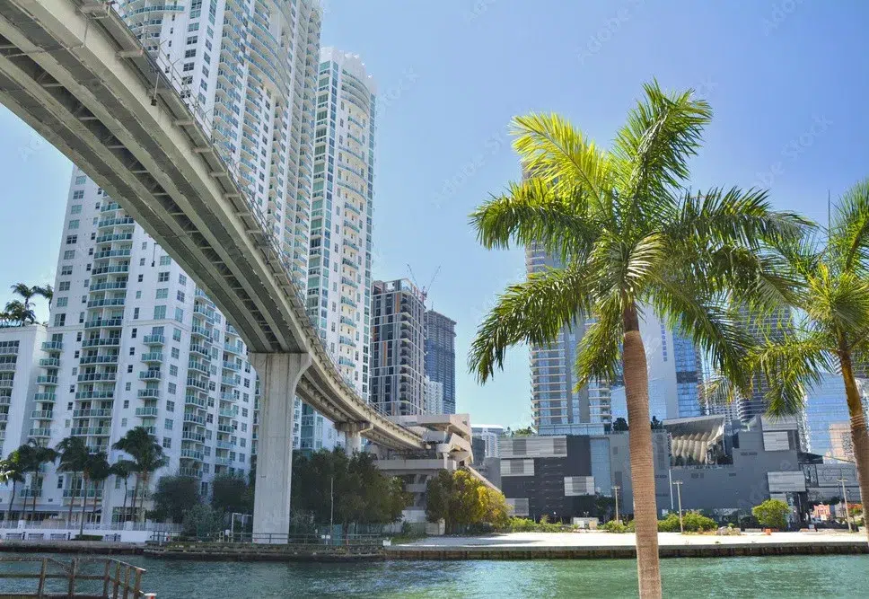 Brickell Miami skyline with Metromover tracks, waterfront views, palm trees, and modern high-rise buildings on a sunny day.