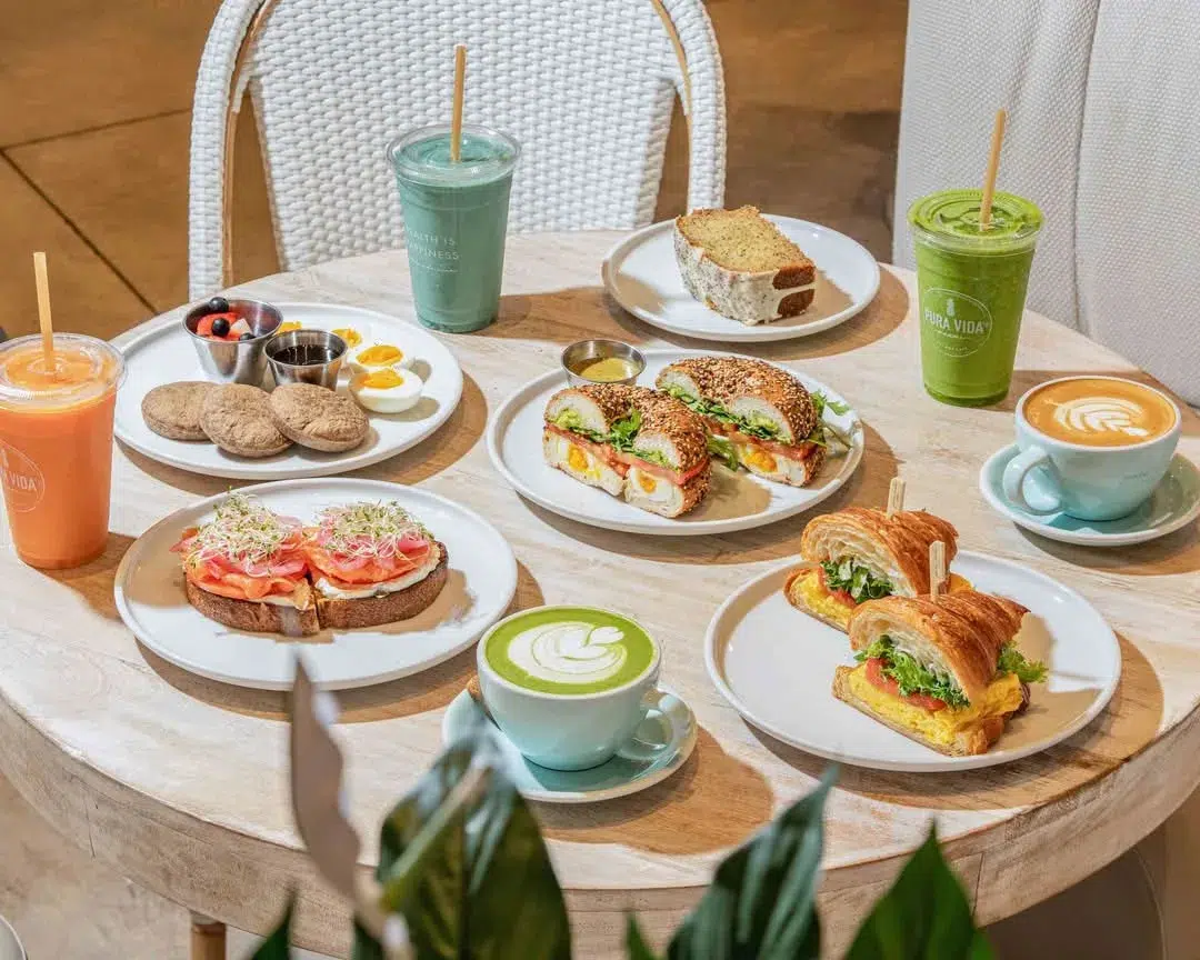 Healthy brunch spread with sandwiches, pastries, coffee, smoothies, and matcha drinks served at a trendy Miami café during Memorial Day Weekend.