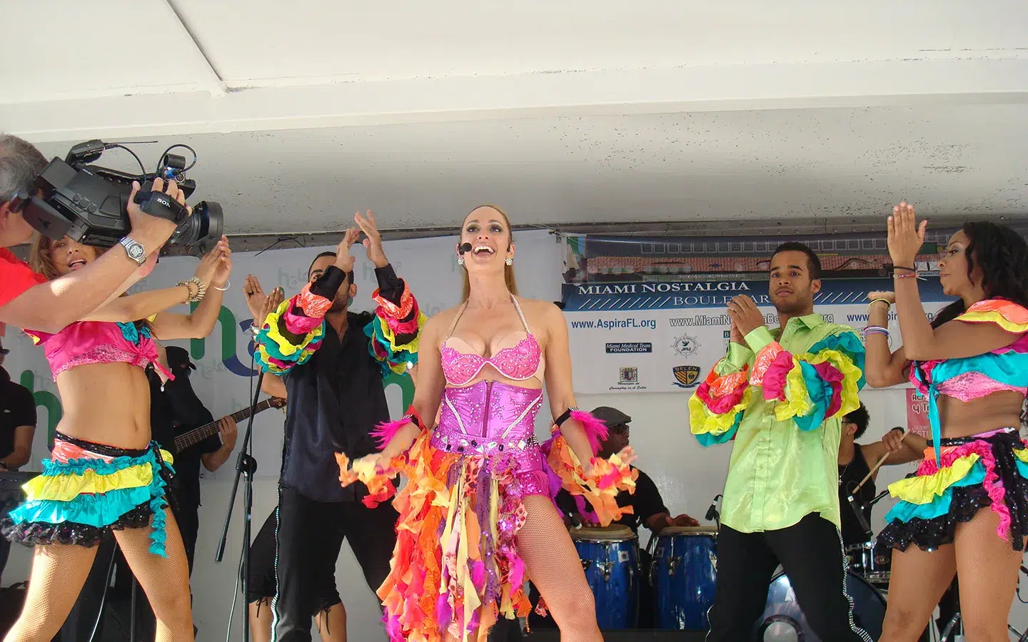 Live Latin dance performance with colorful costumes and musicians entertaining crowds during a cultural event in Miami.