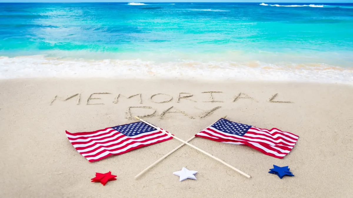 American flags placed on the sand at Miami Beach during Memorial Day weekend with turquoise ocean water in the background.