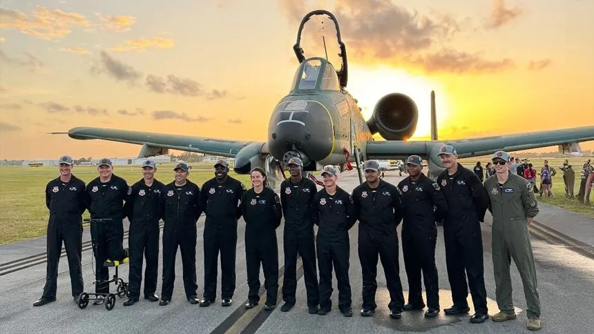 Military aviation crew members standing in front of a U.S. Air Force aircraft during sunset at a Memorial Day Weekend air show event in Miami.