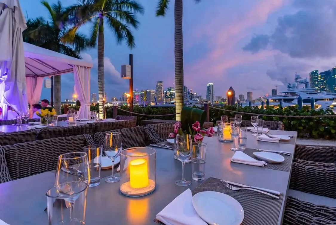 Elegant rooftop dining setup in Miami at sunset with candles, city skyline views, and tropical ambiance
