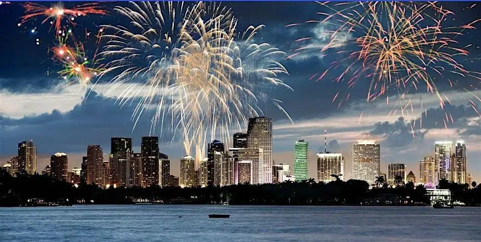 Fireworks burst above the Downtown Miami skyline and Biscayne Bay during a Fourth of July celebration, creating a colorful display over the city's waterfront.