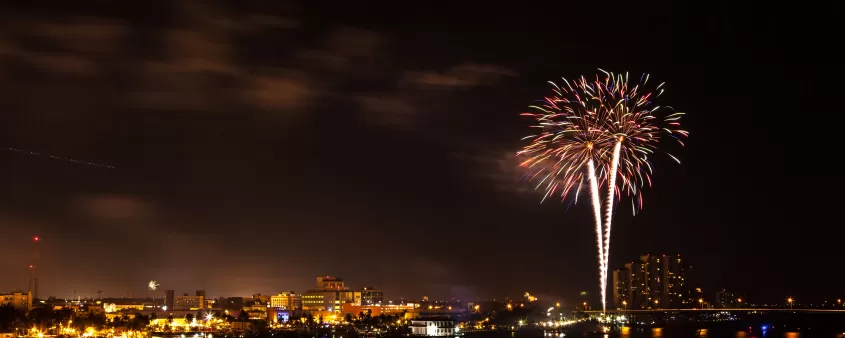 Colorful fireworks explode over the Miami skyline during a Fourth of July celebration, lighting up the night sky above the city's waterfront and downtown district.