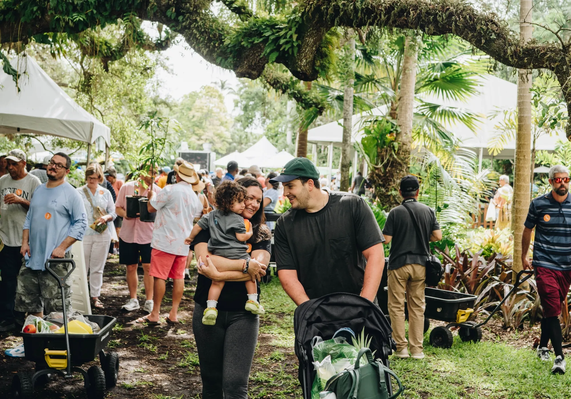 Families and visitors walking through Fairchild Tropical Botanic Garden during the Miami Mango Festival, enjoying tropical landscapes, mango tastings, and outdoor activities.