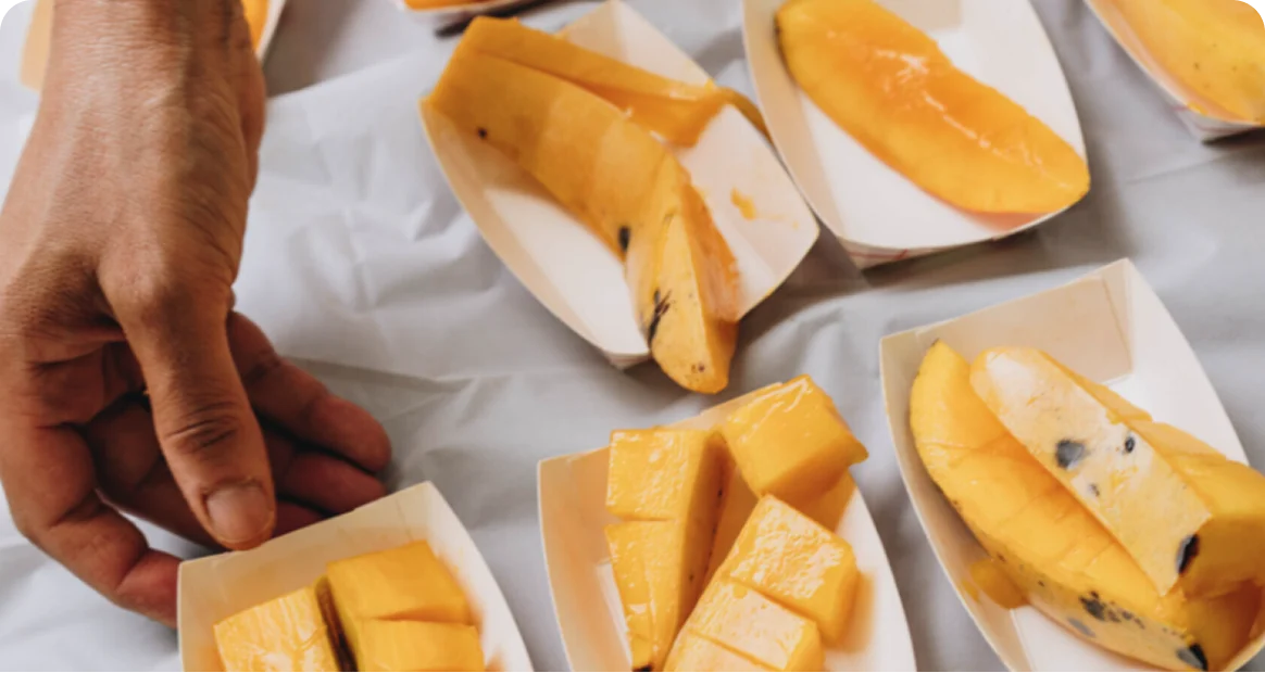 Visitors sampling fresh mango slices during a tasting experience at the Miami Mango Festival, featuring a variety of sweet and tropical mango cultivars.