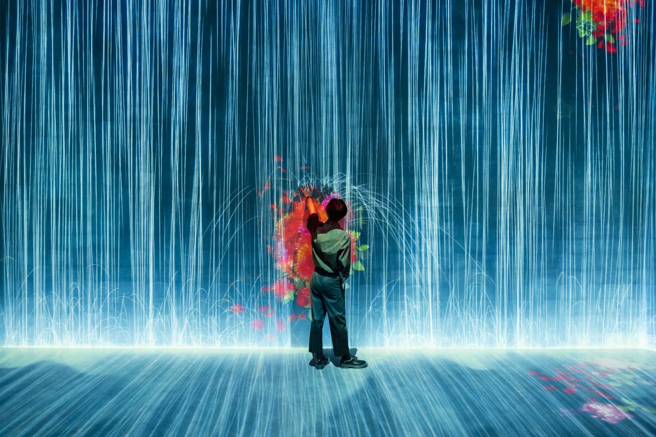 Visitor interacting with a stunning digital waterfall installation at Superblue Miami, surrounded by immersive light projections and interactive contemporary art.
