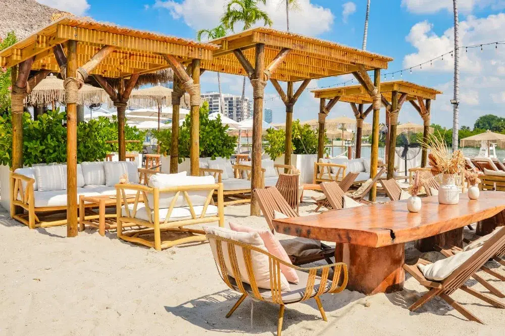 Luxury beachfront cabanas and wooden lounge seating at Joia Beach in Miami, offering a relaxed waterfront setting for Bastille Day celebrations, dining, and summer events.
