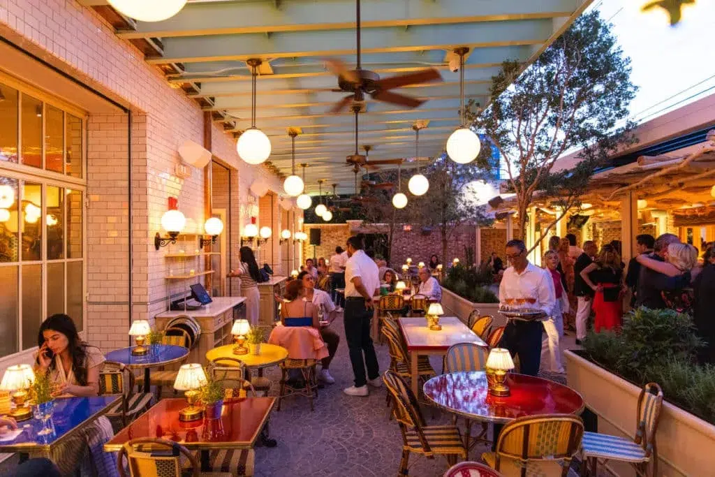 Elegant French-inspired restaurant terrace in Miami with outdoor seating, warm lighting, and guests enjoying dinner during Bastille Day celebrations.