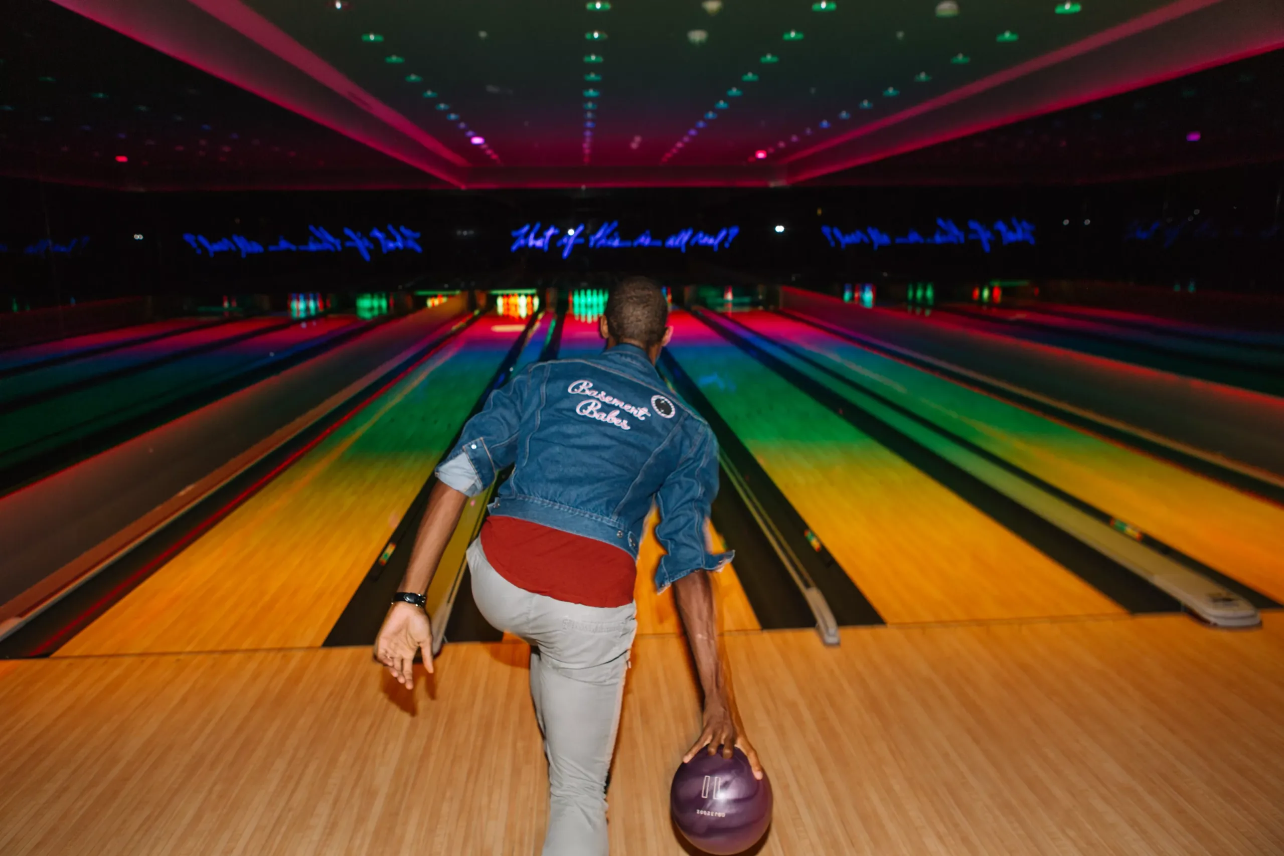Guest bowling under colorful neon lights at Basement Miami, a unique indoor entertainment venue inside The Miami Beach EDITION.