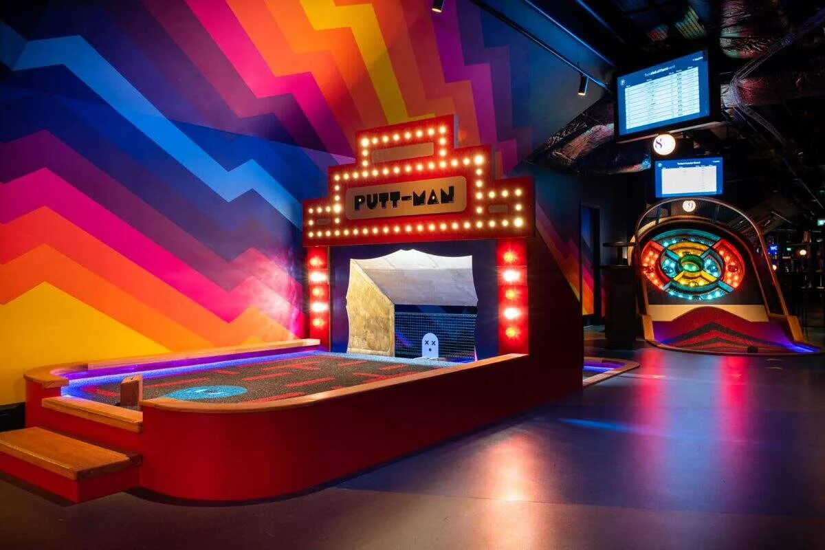Colorful indoor mini golf course at Puttshack Miami featuring interactive holes, vibrant neon décor, and a fun air-conditioned entertainment experience.