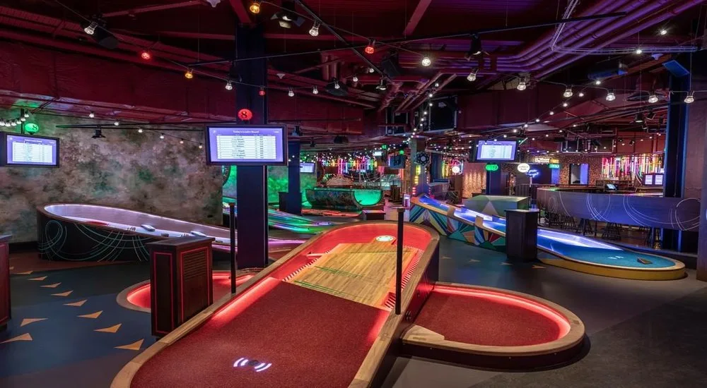 Modern indoor mini golf venue in Miami with illuminated courses, digital scoring, and a lively atmosphere, perfect for escaping the summer heat.