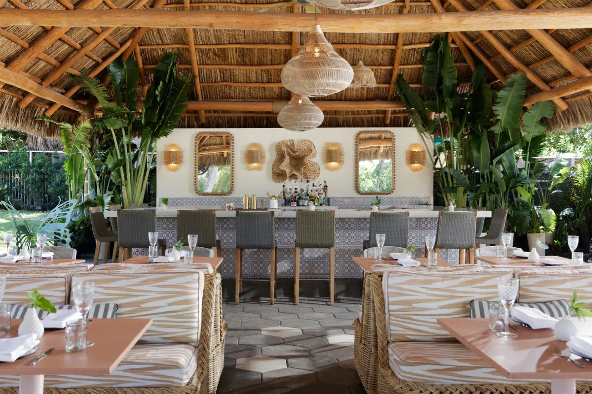 Solei Beach Club dining and bar at the Kimpton Surfcomber Dining area and bar beneath a thatched palapa at Solei Beach Club in Miami Beach